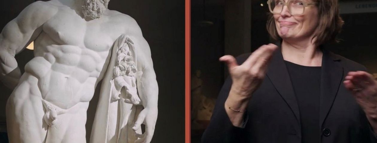 Die Museum Signerin Martina Odorfer während einer Führung im Museum für Abgüsse Klassischer Bildwerke vor einer Herkules-Statue. 