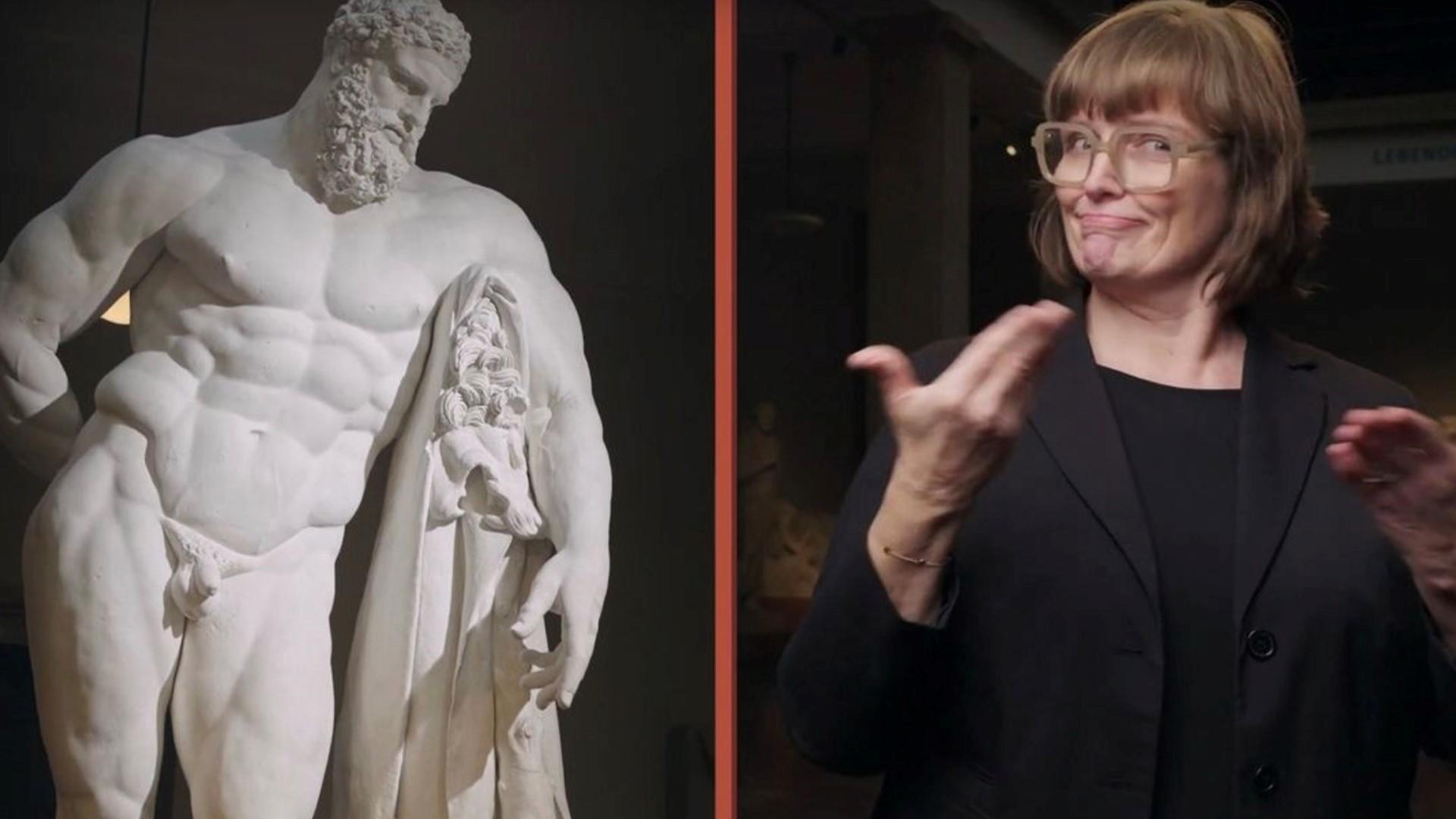 Die Museum Signerin Martina Odorfer während einer Führung im Museum für Abgüsse Klassischer Bildwerke vor einer Herkules-Statue.