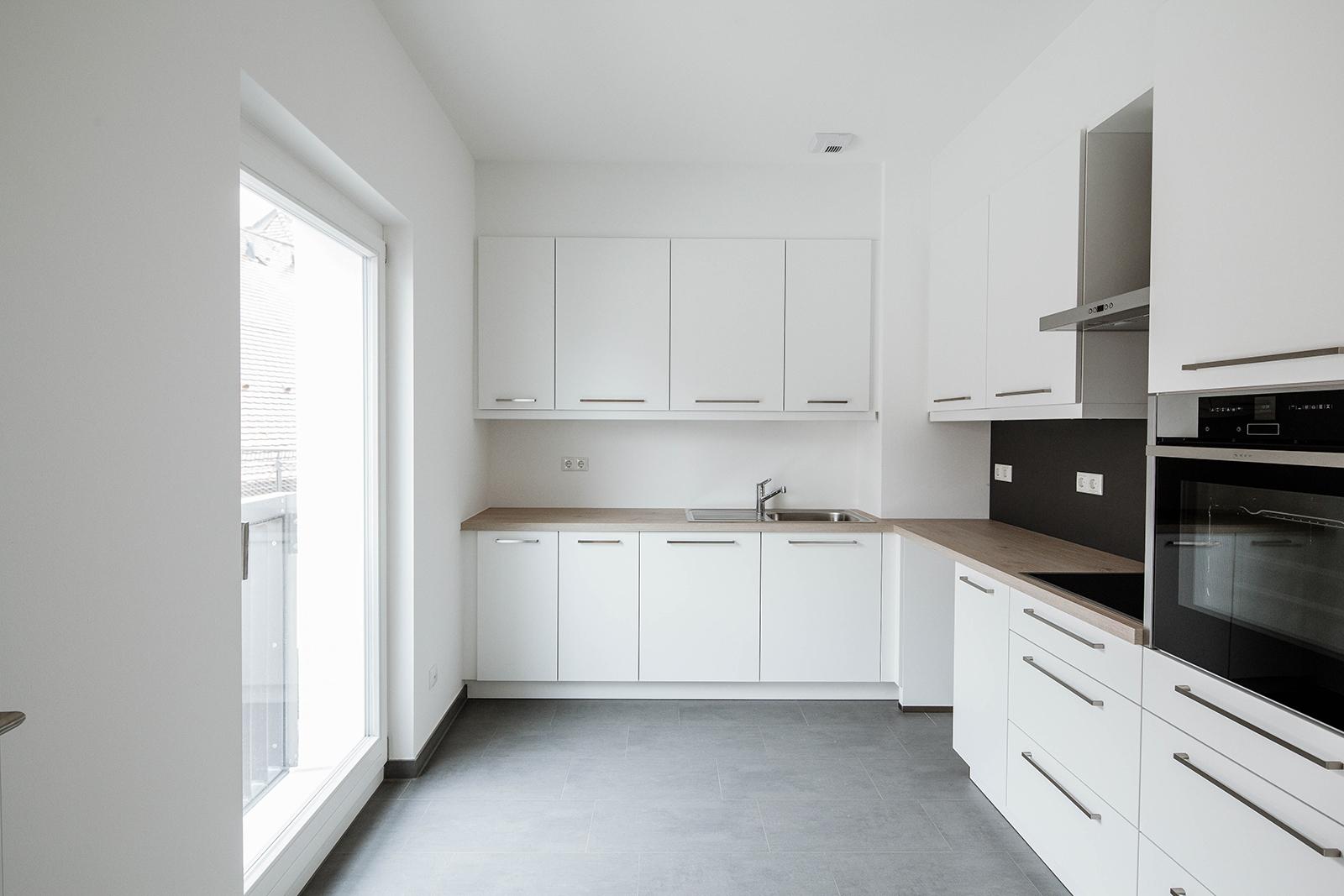 Eine weiße Küchenzeile mit hölzener Arbeitsfläche.