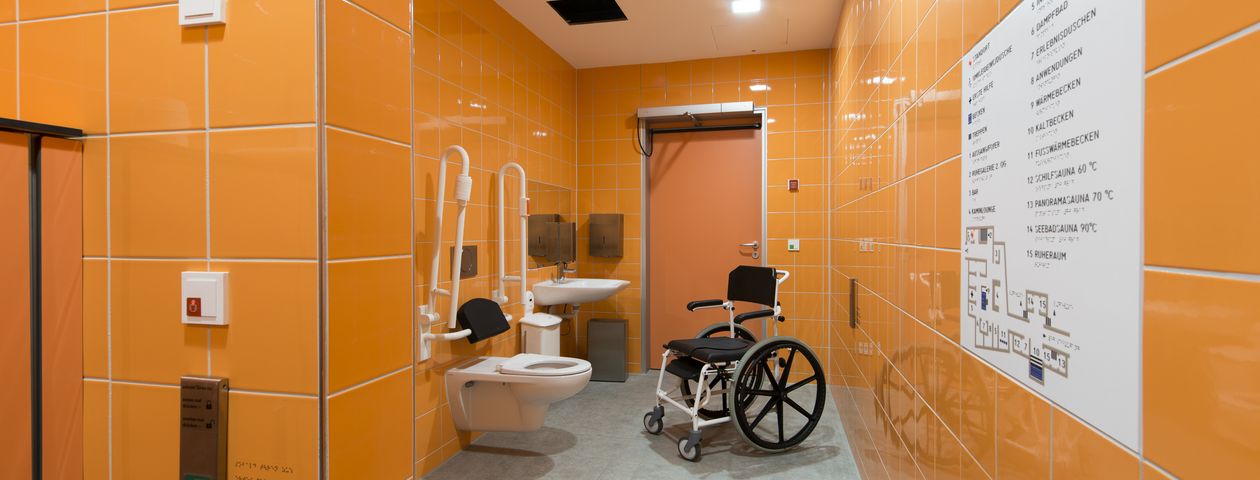 Barrierefreie Toilette und unterfahrbares Waschbecken Barrierefreie Bedienelemente an der Wand wie Notfallknopf und elektrischer Türöffner 