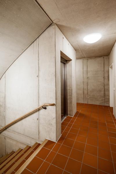 Ein Treppenhaus mit Aufzug in moderner Sichtbetonarchitektur.
