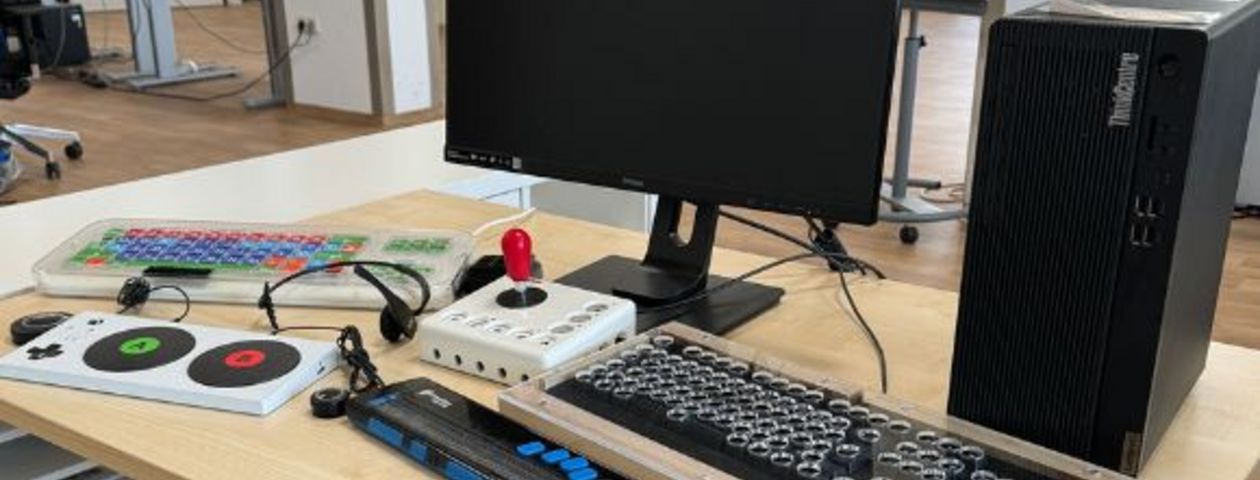 Verschiedene digitale Hilfsmittel wie Tastaturen, Headset und Joystickmaus auf einem Tisch
