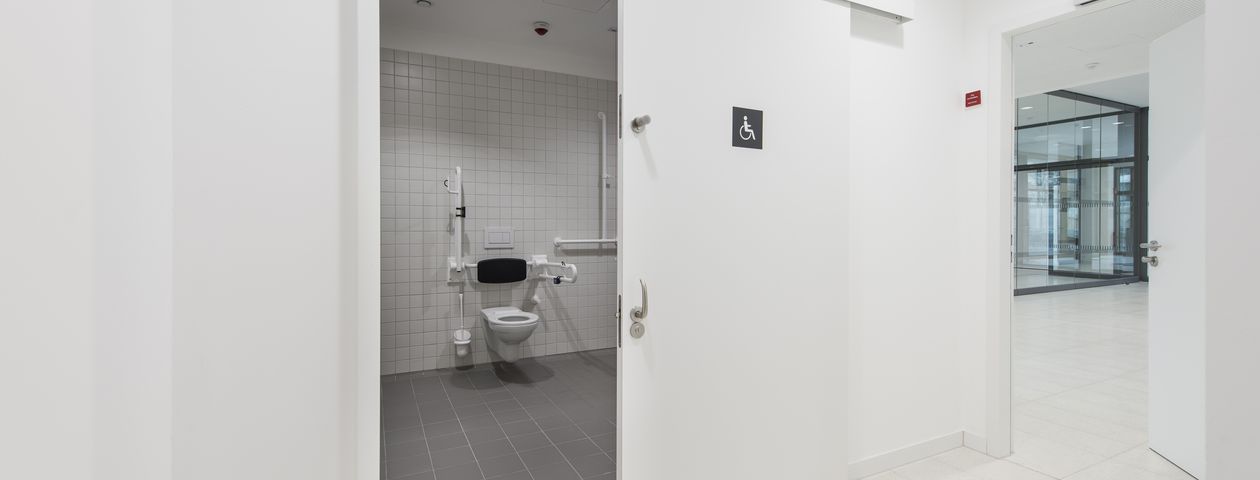 Blick in eine behindertengerechte Toilette mit geöffneter Schiebetüre 